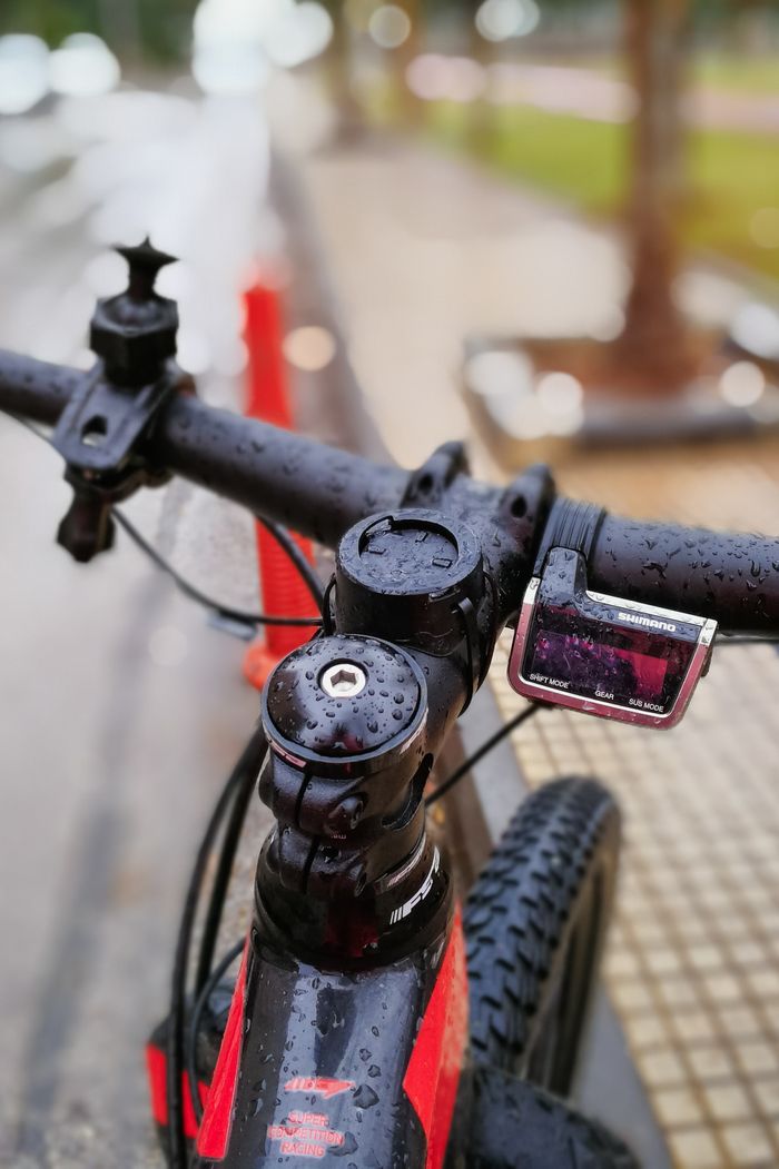 Detailed view of wet bicycle handlebars with raindrops, showcasing outdoor urban cycling in rainy weather.